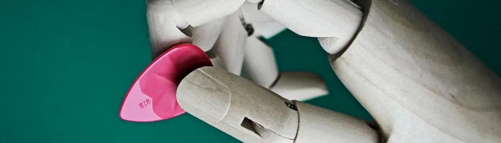 White robotic hand with articulated fingers holding a bright pink heart-shaped object against a teal green background.