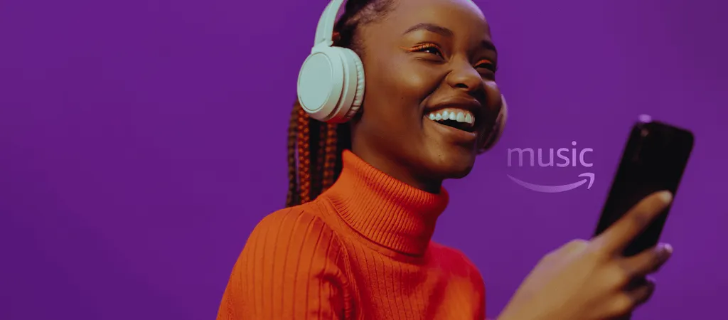 Mujer sonriente con auriculares blancos y suéter naranja sostiene teléfono sobre fondo morado con logo de Amazon Music.