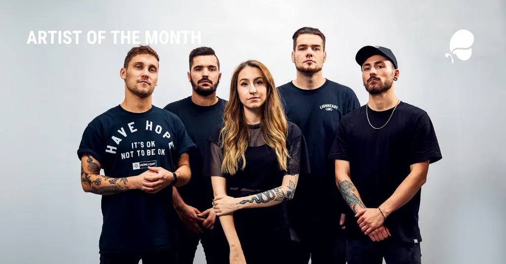 A group of 5 people, 4 men and 1 woman, standing together and wearing black t-shirts. They appear to be the "Artist of the Month" based on the text in the image.