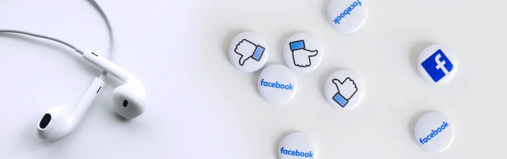 white earbuds and Facebook buttons on a white surface
