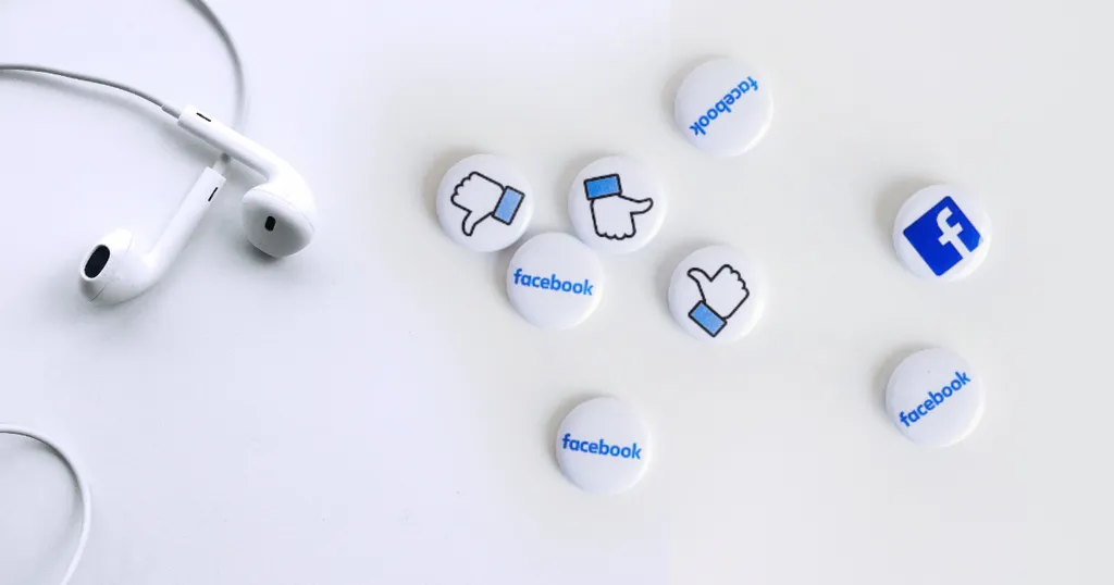 white earbuds and Facebook buttons on a white surface