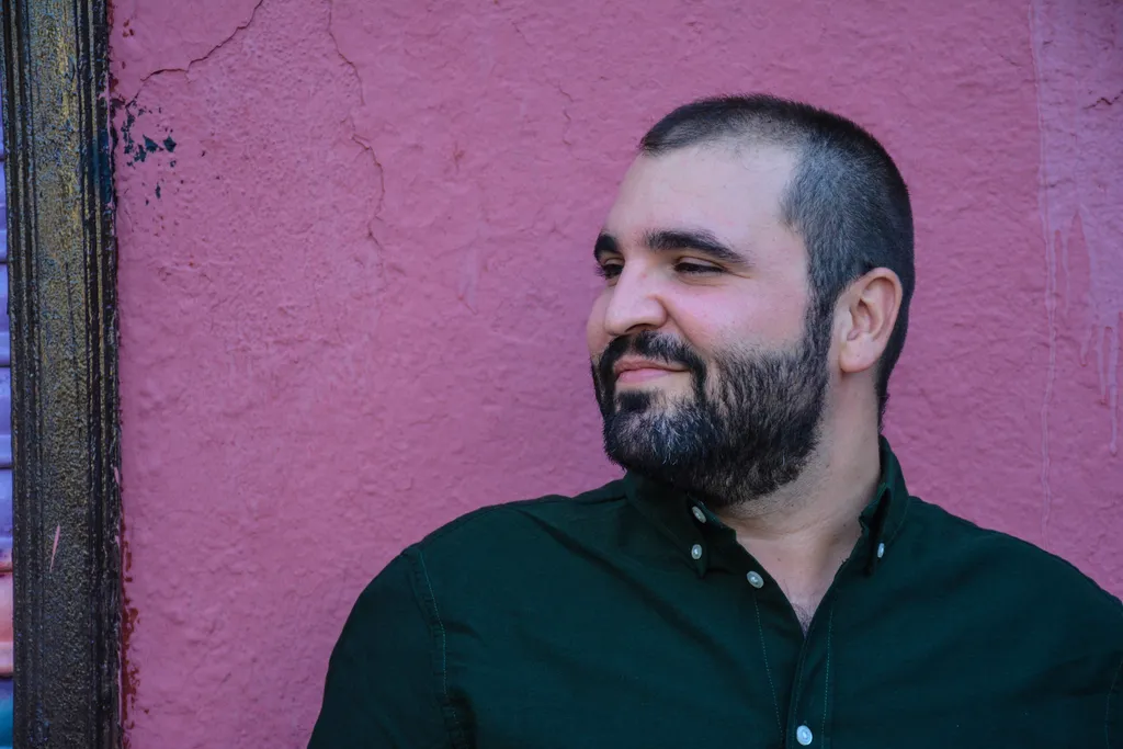 Juan Carlos Lax sobre pared morada por Alejandra López