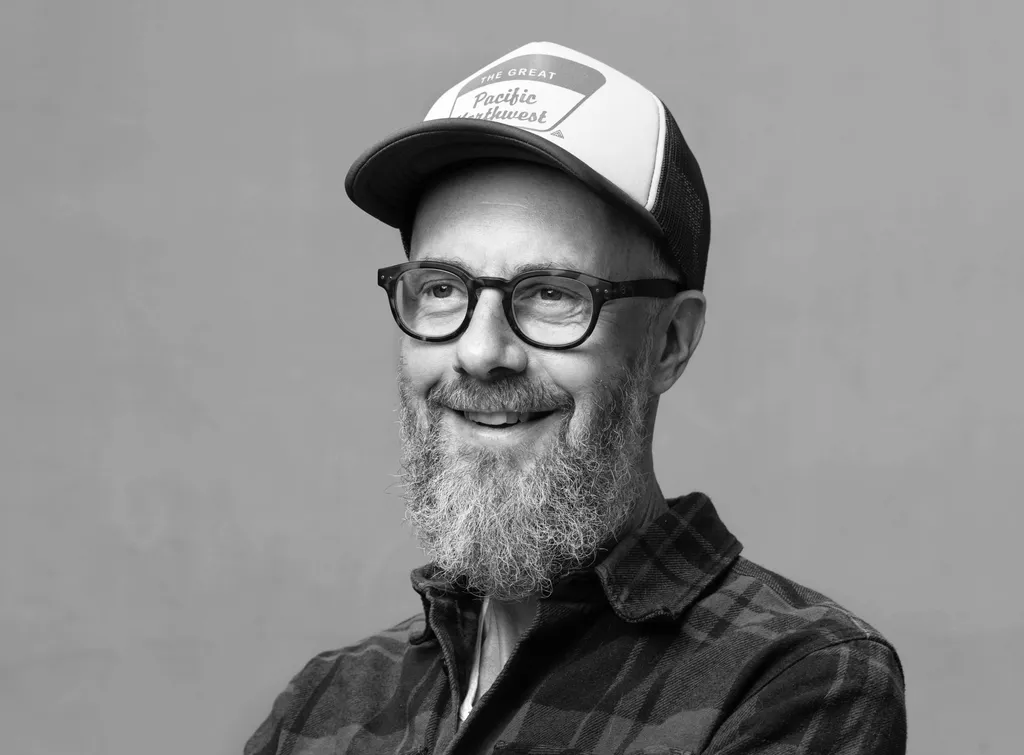 Smiling man with glasses and beard wearing a baseball cap