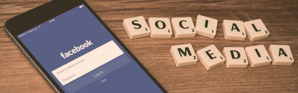 Teléfono mostrando Facebook con Social media formado con fichas al lado