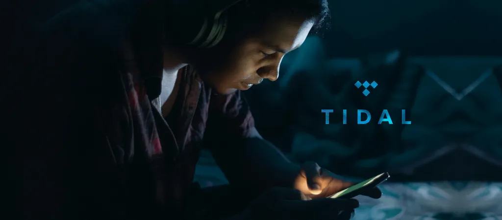 Mulher olhando para smartphone em ambiente escuro com luz azul de tela ao fundo mostrando logo do Tidal.