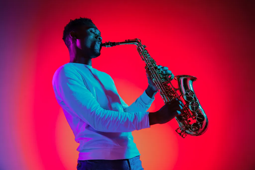 Un uomo che suona un sassofono con luci rosse e blu.