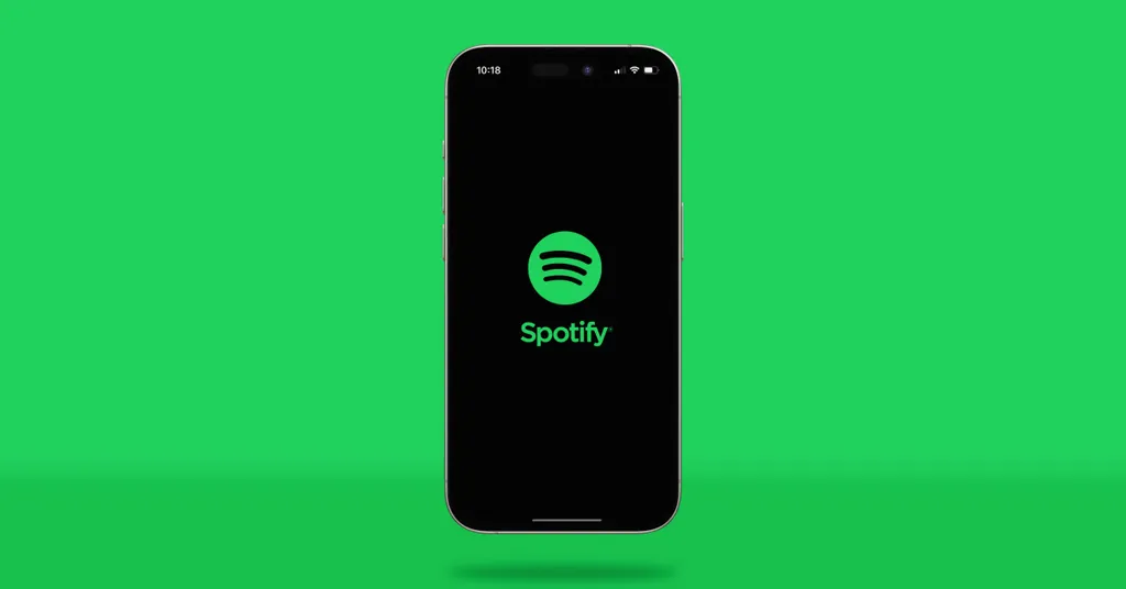 Schwarzes Smartphone mit Spotify-Logo und Schriftzug auf dem Bildschirm, vor hellgrünem Hintergrund