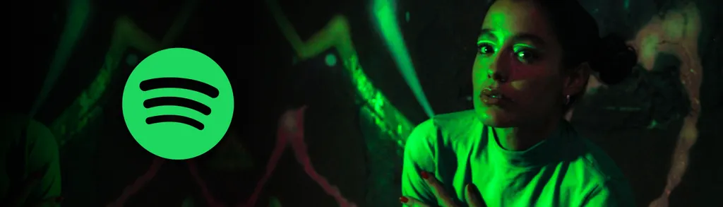 Person wearing headphones in green lighting with Spotify logo visible on left side of dark background.