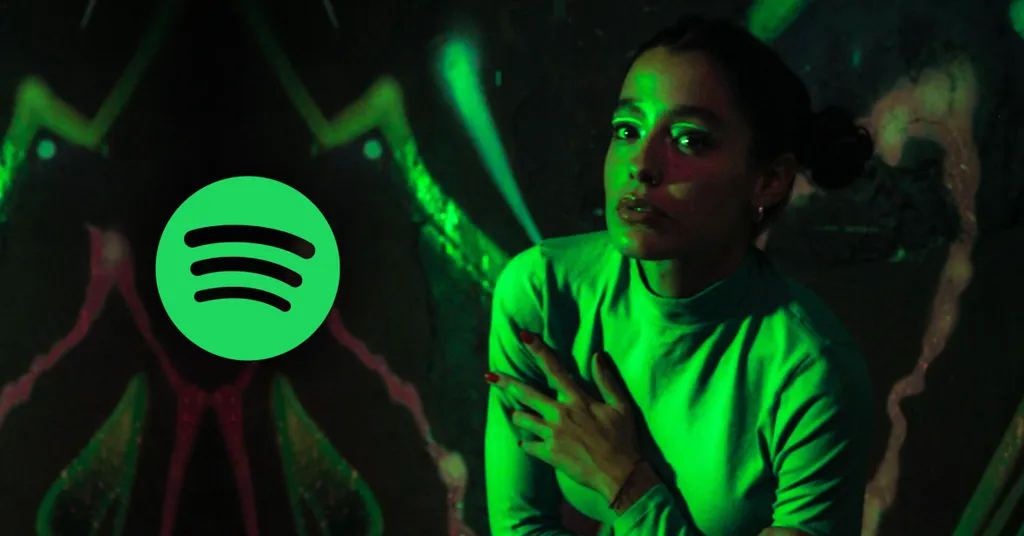 Pessoas dançando sob iluminação verde intensa com logo circular verde do Spotify com três linhas horizontais pretas no canto esquerdo.