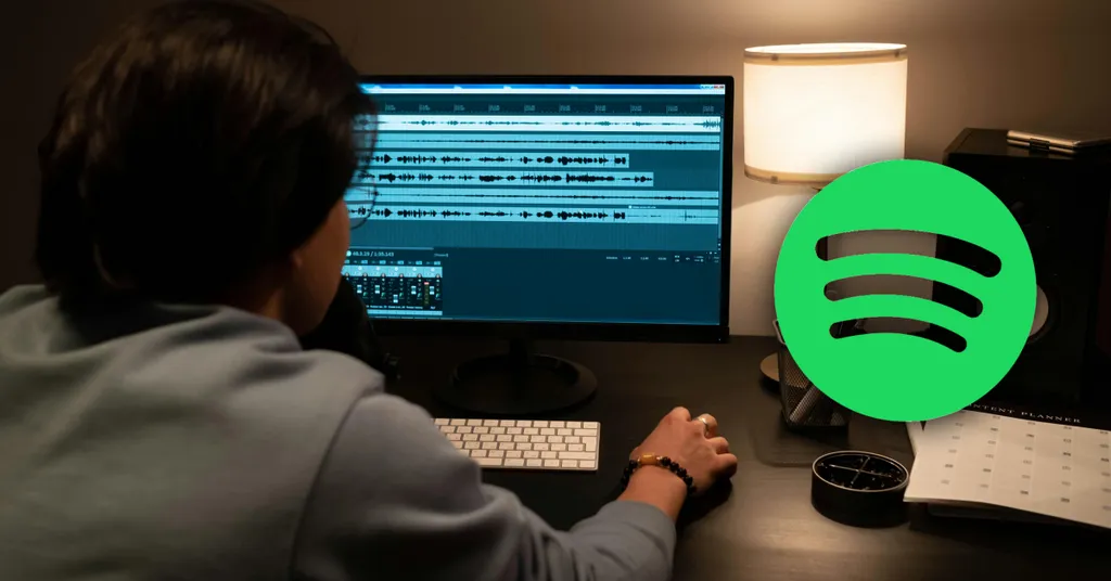 Silhouette of person working on computer, with Spotify icon in foreground.