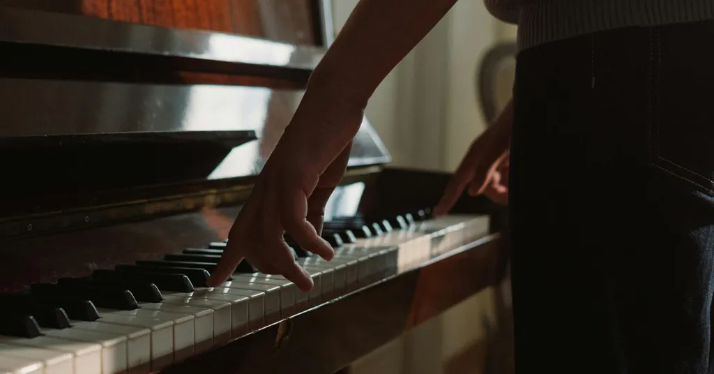Schwarz gekleidete Hand, die Klaviertasten spielt.