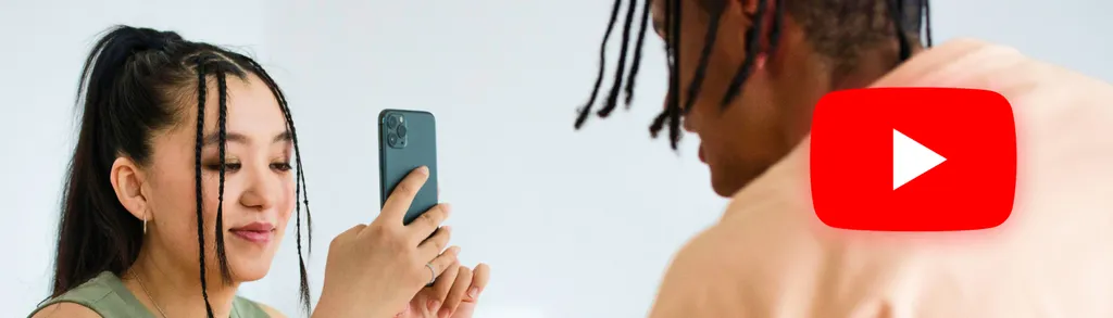 Woman with wet dark hair holding green phone taking selfie with shirtless man with dreadlocks, YouTube logo visible.