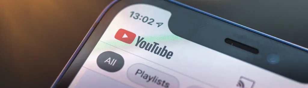 Smartphone screen showing YouTube app interface with time 13:02, "All" and "Playlists" tabs visible at bottom.