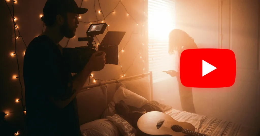 Cameraman riprende in studio con luci calde dorate, attrezzatura video professionale, logo YouTube rosso sovrapposto